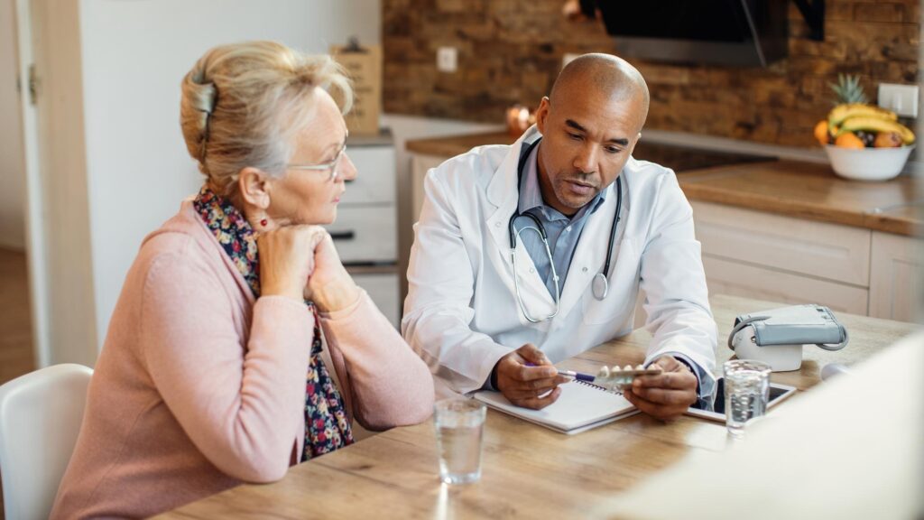 African American doctor talking about medicines with mature woman during home visit