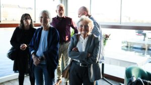 Group of people standing indoors near a window