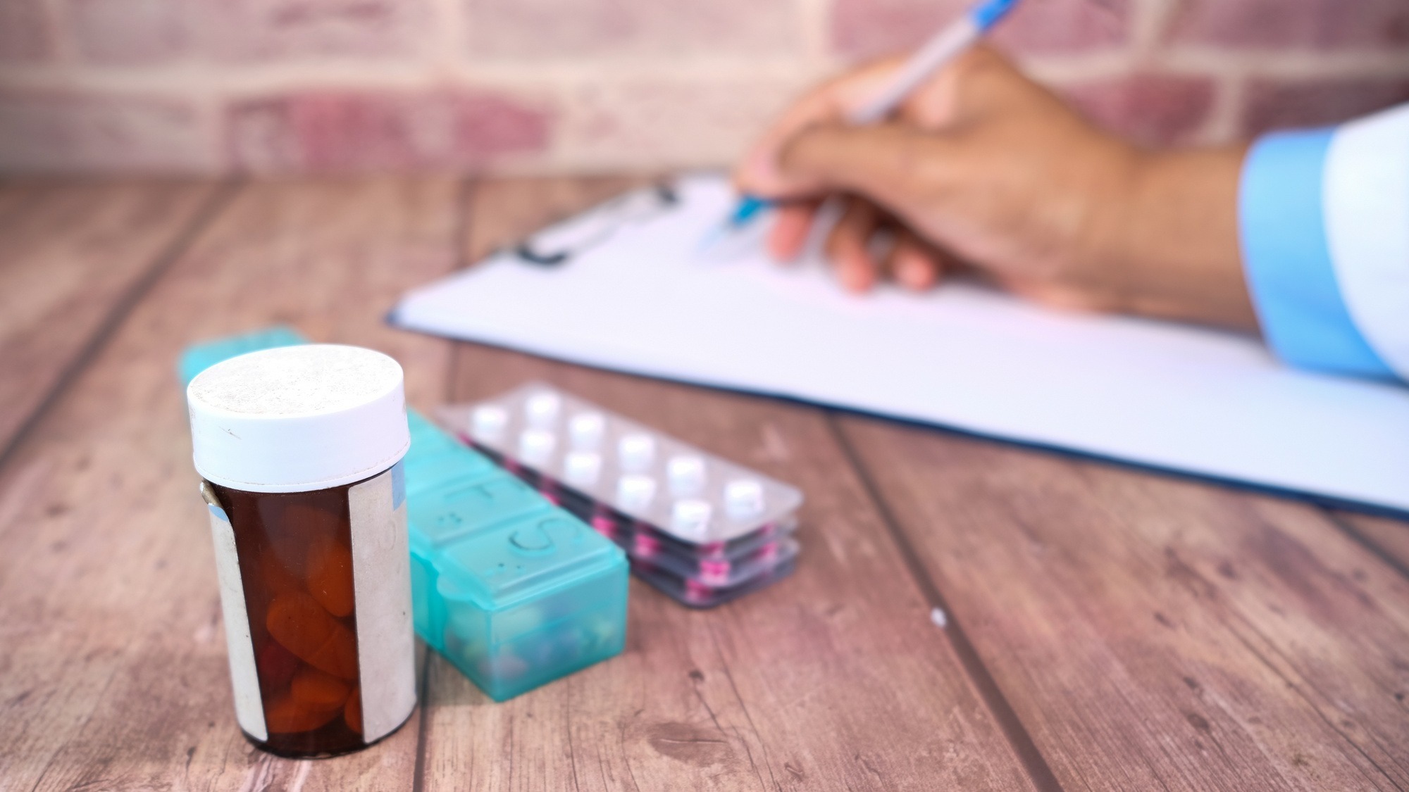 Selective focus. doctor writing on paper and pills contianer on clinic table . Selective focus. doctor writing on paper and pills contianer on clinic table .