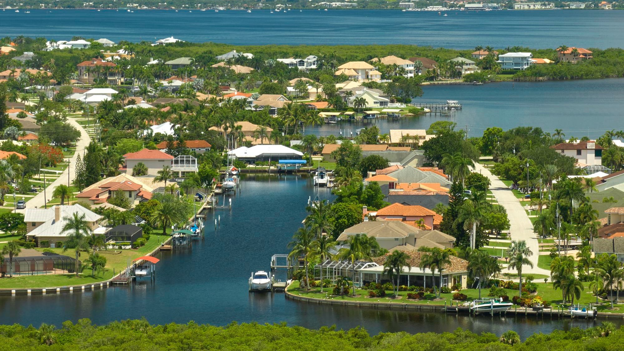 Aerial view of residential suburbs with one storey houses located near wildlife wetlands with green tropical vegetation on sea shore Living close to nature in warm climate concept Aerial view of residential suburbs with one storey houses located near wildlife wetlands with green tropical vegetation on sea shore Living close to nature in warm climate concept