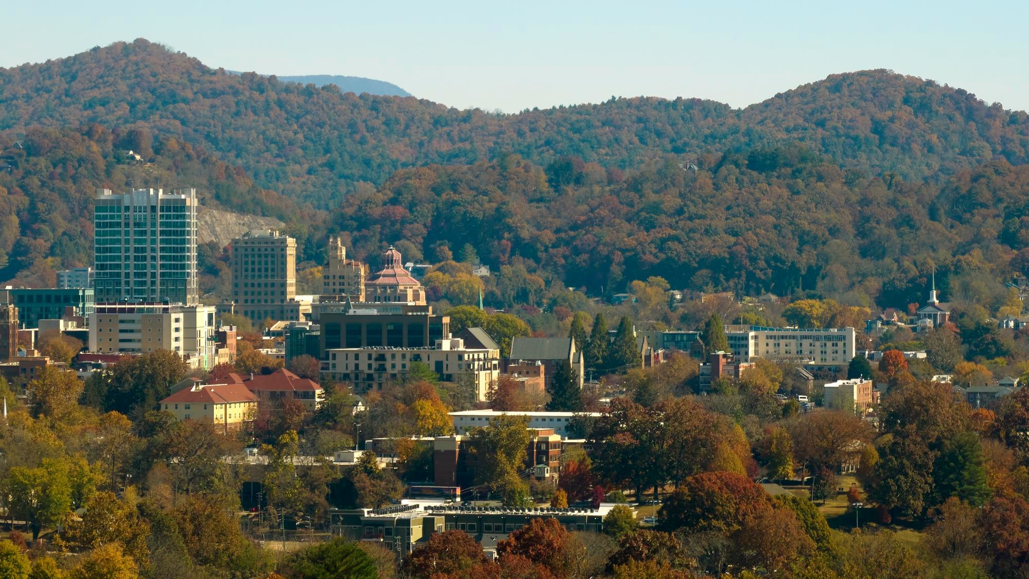 Aerial view of Asheville city in North Carolina with high buildings and mountain hills in distance Aerial view of Asheville city in North Carolina with high buildings and mountain hills in distance