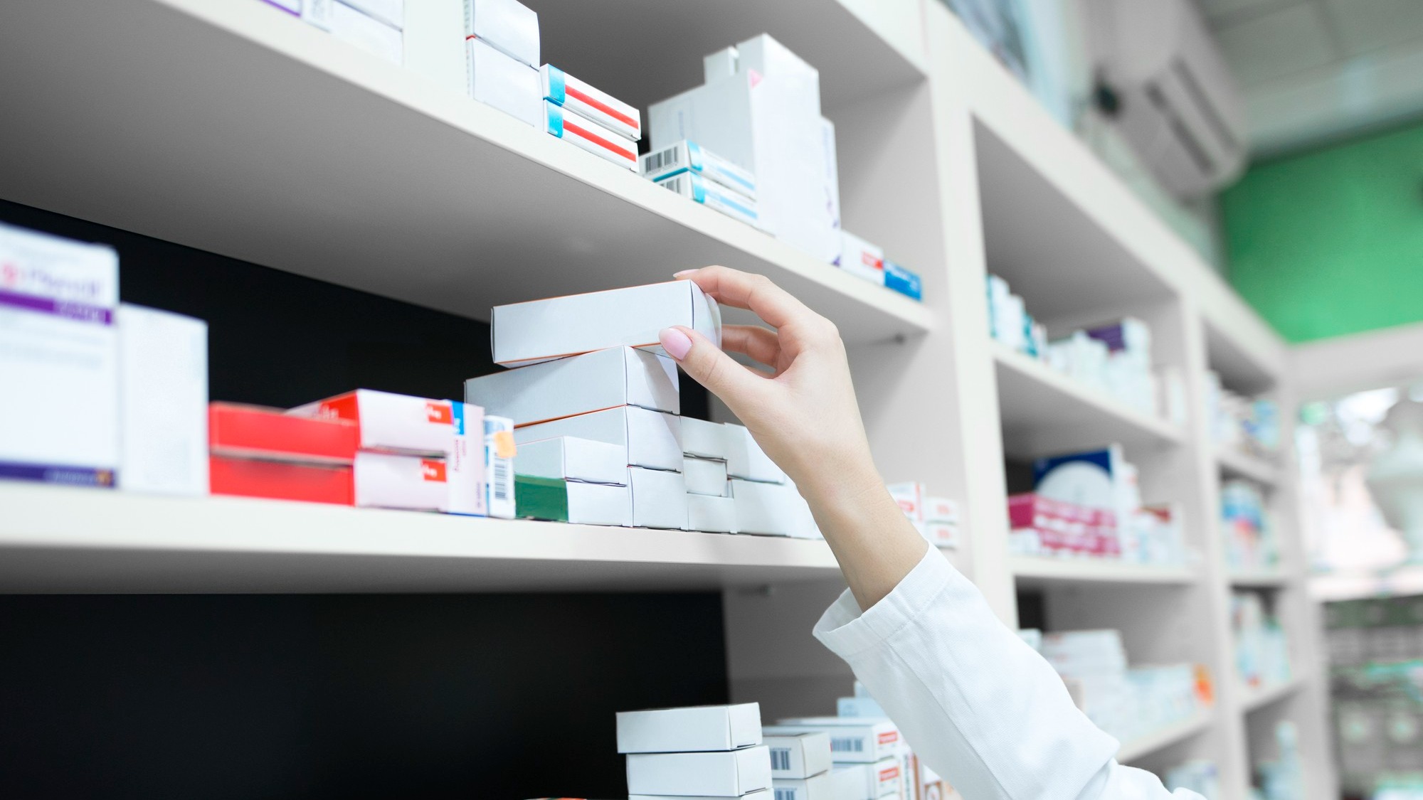 Closeup view of pharmacist hand taking medicine box from the shelf in drug store Closeup view of pharmacist hand taking medicine box from the shelf in drug store
