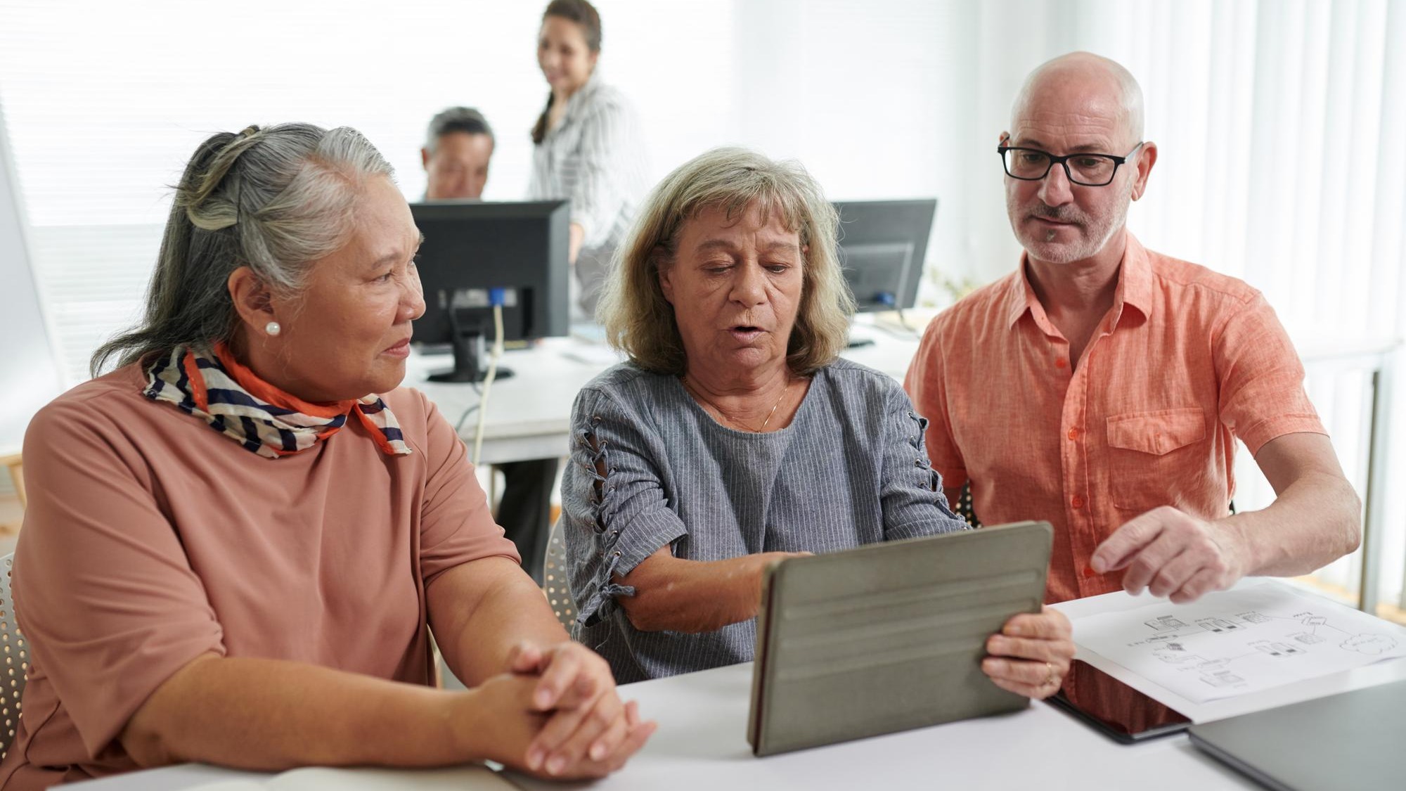 Senior men and women discussing how to install application on digital tablet Senior men and women discussing how to install application on digital tablet