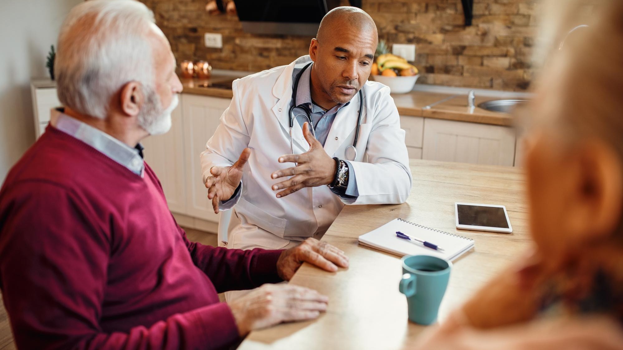 African American doctor communicating with mature couple during home visit African American doctor communicating with mature couple during home visit