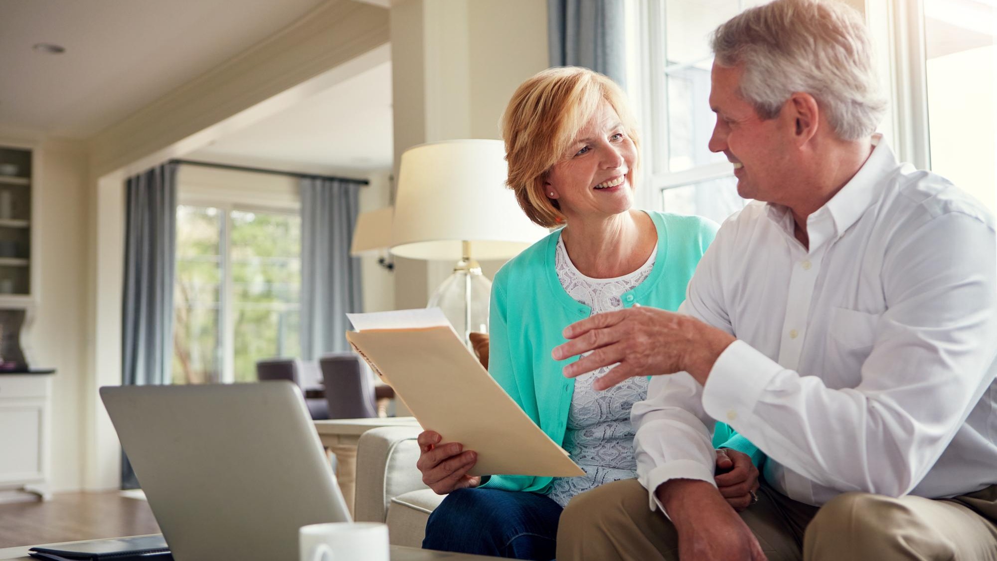 Paperwork laptop and mature couple on sofa with financial report insurance and investment in home Retirement marriage and senior man and woman on computer for finance budget pension or mortgage
