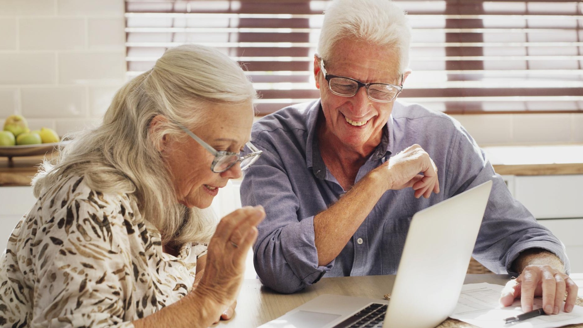 Documents finance and laptop with old couple in kitchen of home for bank or budget review Computer investment and paperwork with happy senior people in apartment for savings growth or success