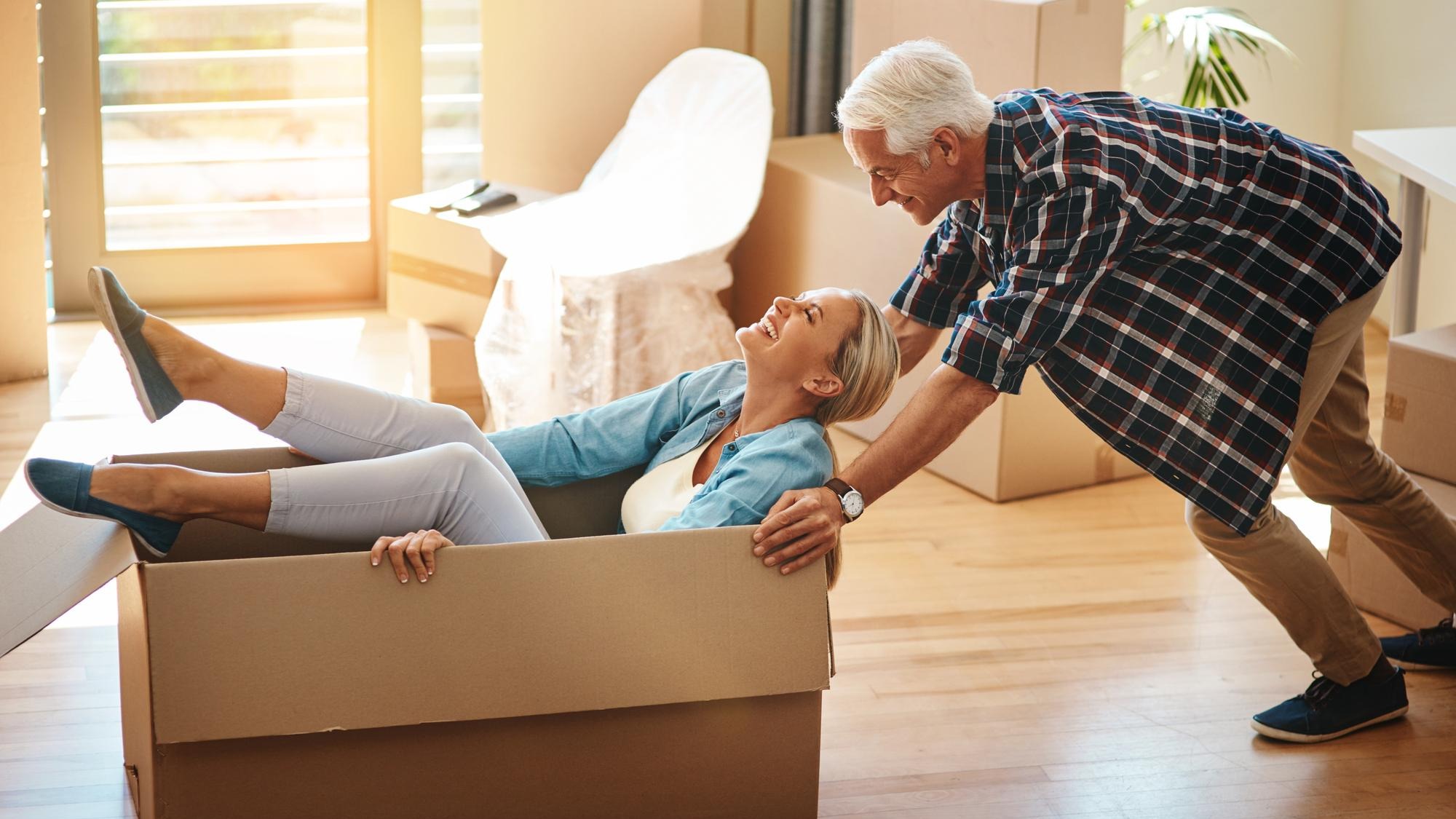 Happy couple play and boxes in new house with moving celebration and excited for mortgage or relocation in USA Mature man and woman in cardboard with wellness energy and joy for home and bonding Happy couple play and boxes in new house with moving celebration and excited for mortgage or relocation in USA Mature man and woman in cardboard with wellness energy and joy for home and bonding