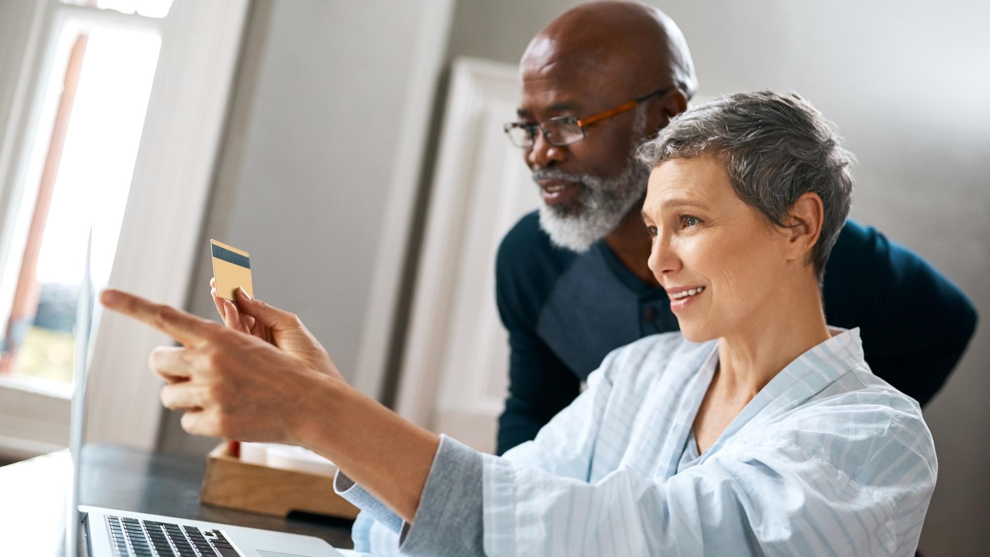 Laptop online shopping and retirement with senior interracial couple in home together for bank payment Computer credit card or ecommerce with happy man and woman in apartment for internet purchase