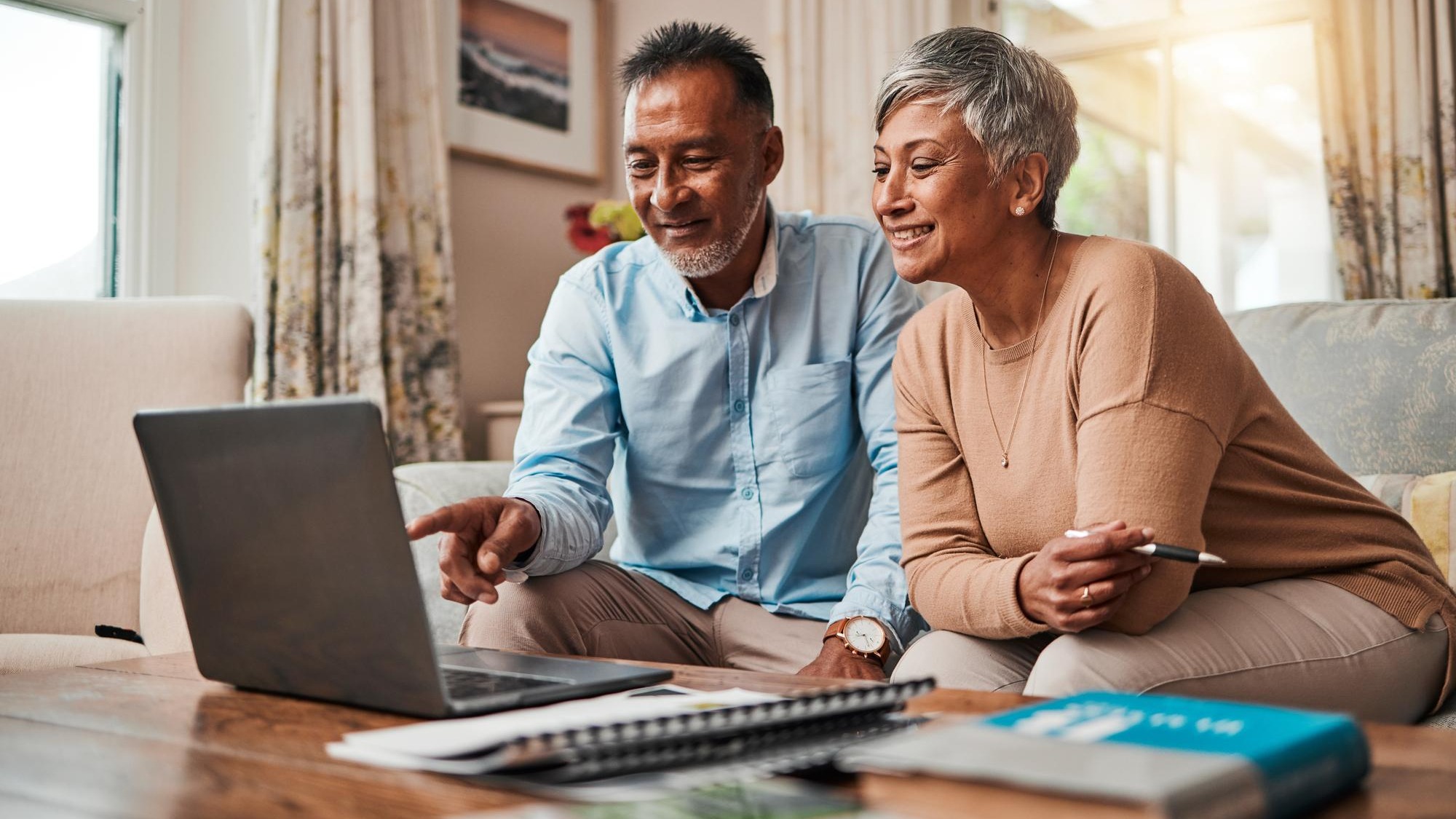 Mature couple sofa and laptop for planning finance retirement funding and investment or asset management at home Elderly people or man and woman reading information on computer for pension savings Mature couple sofa and laptop for planning finance retirement funding and investment or asset management at home Elderly people or man and woman reading information on computer for pension savings