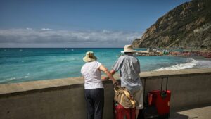 man and woman standing beside concrete seawall looking at beach