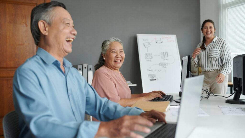 Senior couple having fun in computer class they are typing and joking around