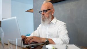 Medium shot senior man typing on keyboard
