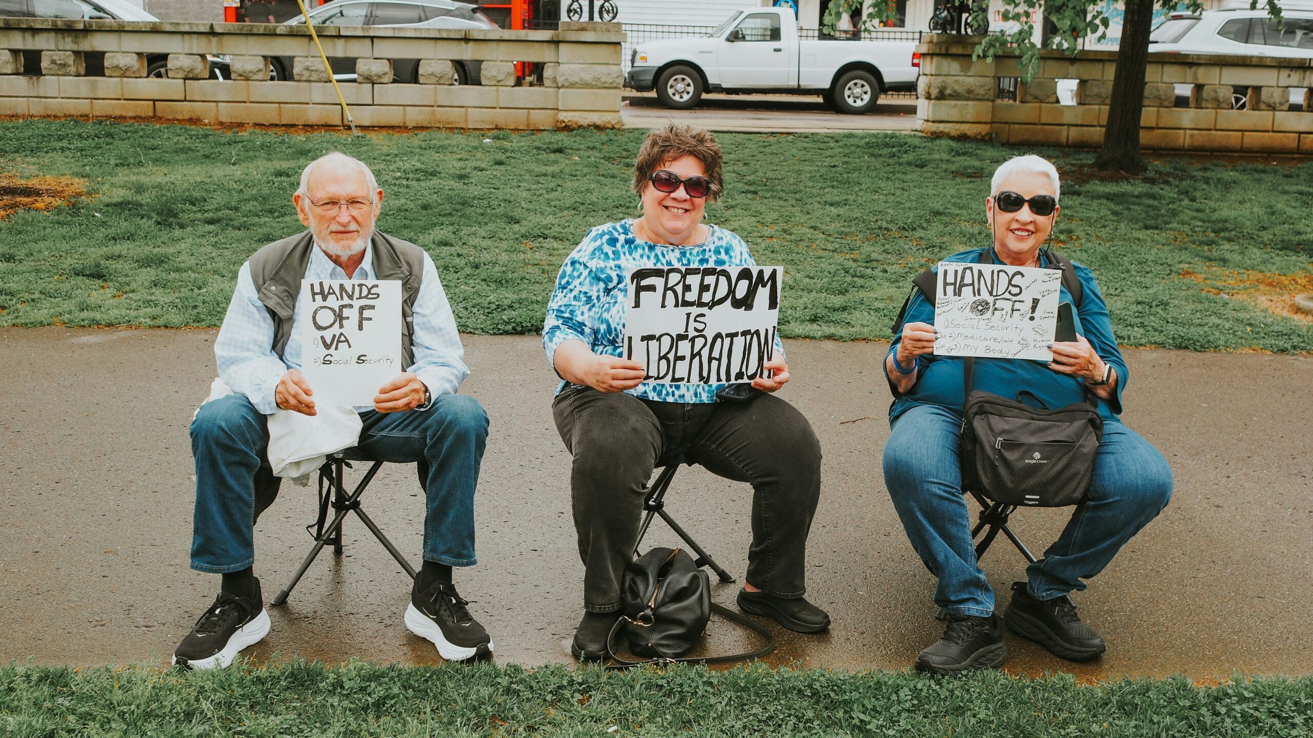 Three people are holding signs during a protest.