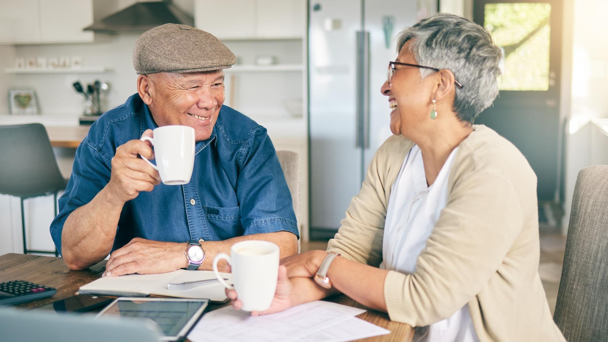 Laptop happy or old couple with budget paperwork mortgage or banking documents at home Coffee drink mature woman or senior man laughing at financial bills or investment portfolio in retirement Laptop happy or old couple with budget paperwork mortgage or banking documents at home Coffee drink mature woman or senior man laughing at financial bills or investment portfolio in retirement