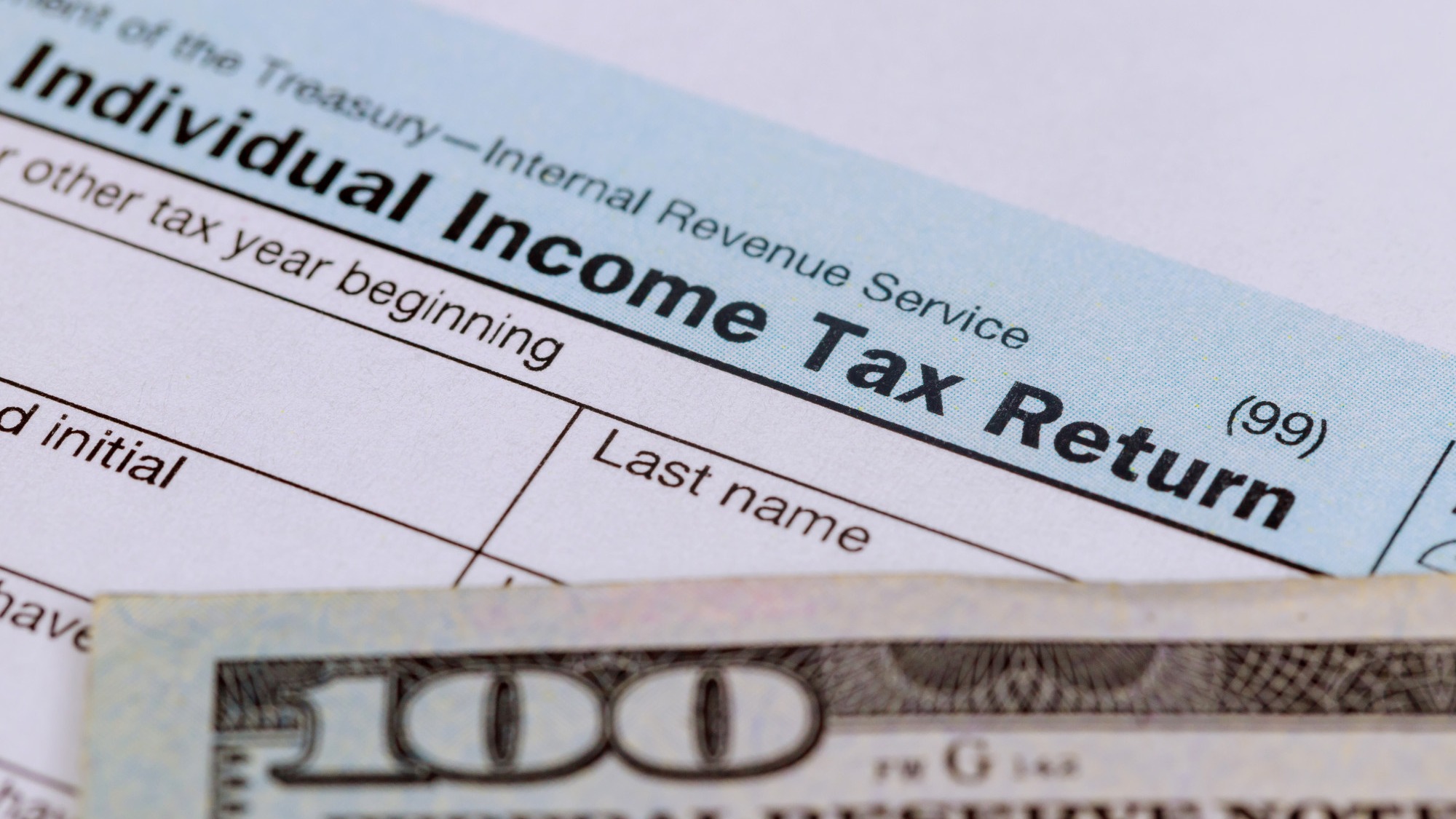 Tax time Closeup of U.S. 1040 tax return with 100 bills Tax time Closeup of U.S. 1040 tax return with 100 bills
